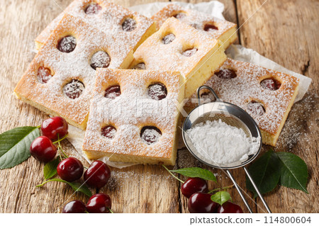 Bublanina Czech and Slovakian Cherry Bubble Cake with sprinkled with powdered sugar closeup on the parchment. Horizontal 114800604