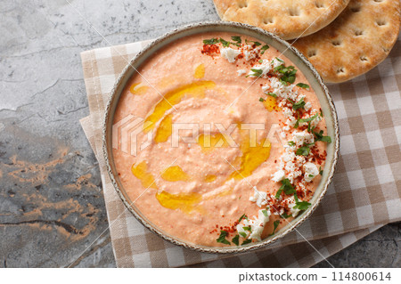 Tirokafteri is a Greek spicy feta dip with creamy cheese, roasted red peppers, garlic and chilli closeup on the bowl. Horizontal top view 114800614
