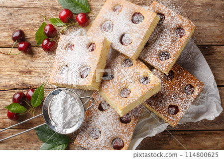 Fruity cherry cake known as Bublanina sprinkled with powdered sugar closeup on the parchment. Horizontal top view 114800625