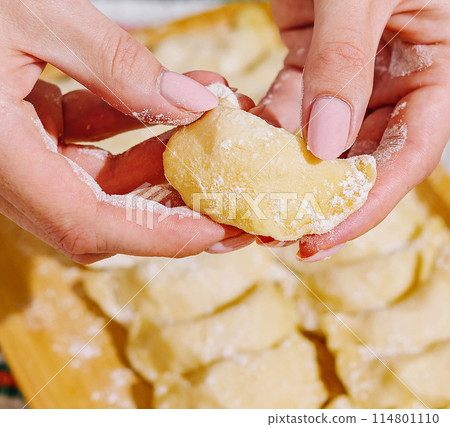 Close-up of hands shaping pierogi on a kitchen board Close-up of hands shaping pierogi on a kitchen board 114801110