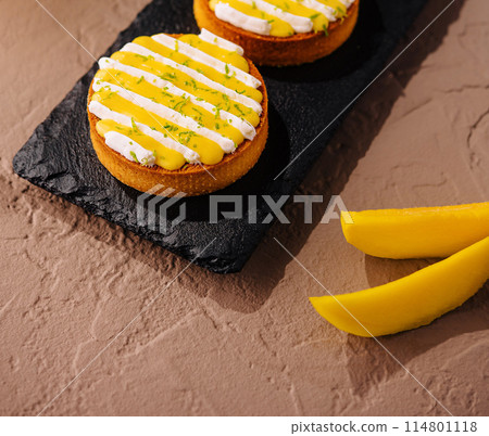 Gourmet mango tarts on slate platter 114801118