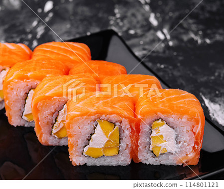 Fresh salmon sushi roll on elegant black plate 114801121