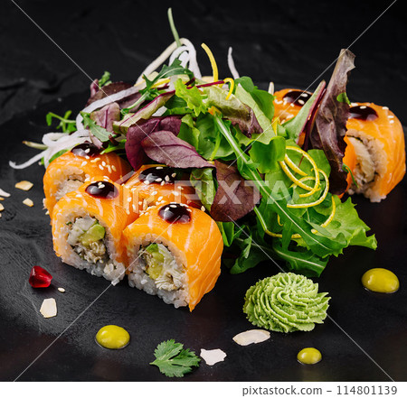 Gourmet sushi roll with fresh greens on elegant black plate Gourmet sushi roll with fresh greens on elegant black plate 114801139