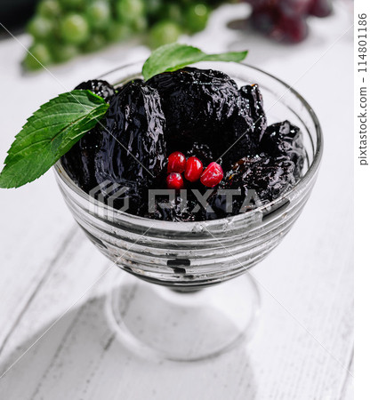 Gourmet fresh prunes in glass bowl with mint garnish Gourmet fresh prunes in glass bowl with mint garnish 114801186
