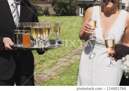 A waiter serving champagne at a wedding for the bride and a groom A waiter serving champagne at a wedding for the bride and a groom 114801766