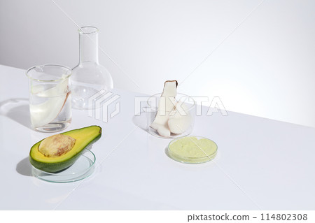 Experiment instruments containing transparent liquid with avocado and coconut and a petri dish with cream, placed on white table top over the same color background, space for showing product Experiment instruments containing transparent liquid with avocado and coconut and a petri dish with cream, placed on white table top over the same color background, space for showing product 114802308