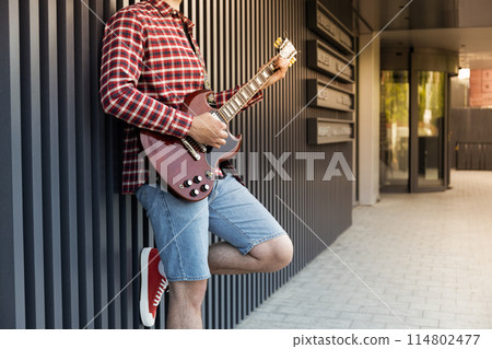 Stylish young guy playing guitar on the street 114802477