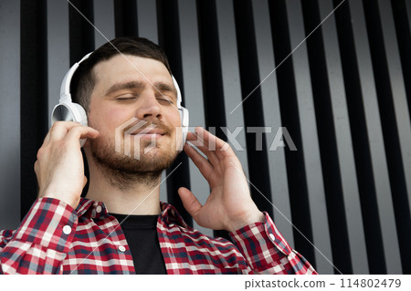 Attractive young guy listens to music in headphones 114802479