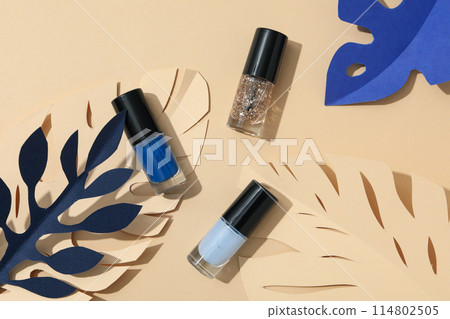 Multicolored nail polishes with decorative paper leaves 114802505