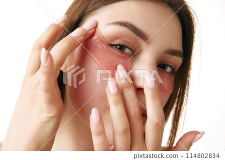 Woman with under-eye patches poses against white background. Girl look fresh and clean, emphasizing beauty care routine. 114802834