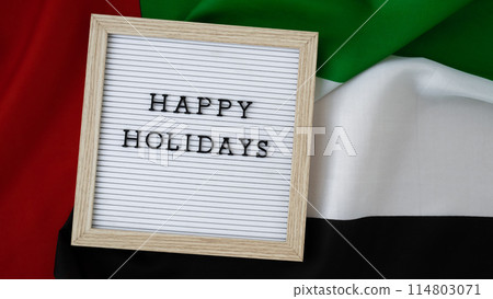 Text HAPPY HOLIDAYS on background waving flag of UAE. Independence Commemoration Day Muslim, Ramadan, Day of flag National holiday of United Arab Emirates. Arabian holidays. Dubai 114803071
