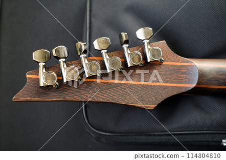 Close-up of rosewood electric guitar strings headstock and fretboard rest on a plush guard Close-up of rosewood electric guitar strings headstock and fretboard rest on a plush guard 114804810