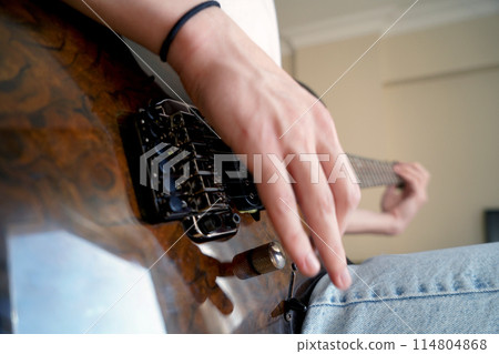 Hands of a Caucasian musician playing an electric guitar, playing a brown wooden electric guitar Hands of a Caucasian musician playing an electric guitar, playing a brown wooden electric guitar 114804868