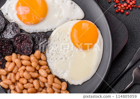 English breakfast with fried eggs, bacon, beans, tomatoes, spices and herbs English breakfast with fried eggs, bacon, beans, tomatoes, spices and herbs 114805059