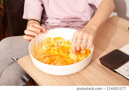 Caucasian person in pink t-shirt holding plate full of potato chips and preparing to eat Caucasian person in pink t-shirt holding plate full of potato chips and preparing to eat 114805277