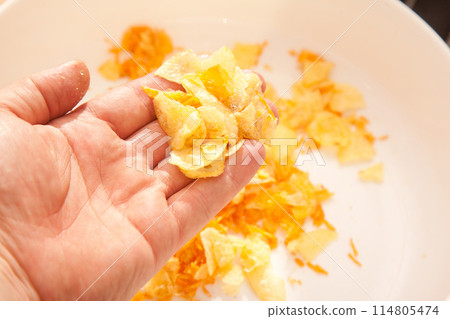 There are potato chips in a white plate, a caucasian person is holding potato chips in his hand 114805474