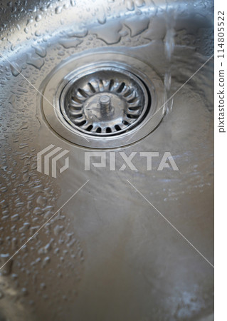 Stainless steel sink and water drain in a modern kitchen, water flow in the kitchen sink 114805522
