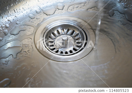 Stainless steel sink and water drain in a modern kitchen, water flow in the kitchen sink Stainless steel sink and water drain in a modern kitchen, water flow in the kitchen sink 114805523