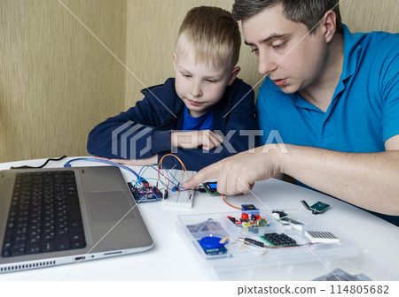 Programming for children. A teacher teaches a child at a robotics and IT school. Boy learning to code control board 114805682