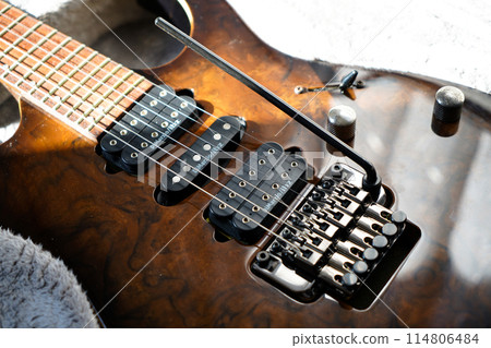 Electric guitar bridge, strings and pickup, detail close-up view of guitar pickup in wood walnut Electric guitar bridge, strings and pickup, detail close-up view of guitar pickup in wood walnut 114806484