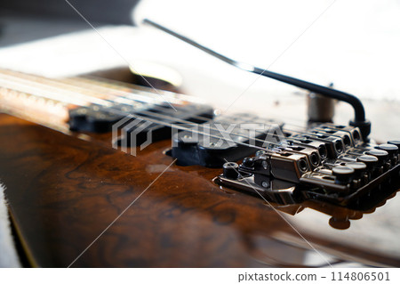 Electric guitar bridge, strings and pickup, detail close-up view of guitar pickup in wood walnut Electric guitar bridge, strings and pickup, detail close-up view of guitar pickup in wood walnut 114806501