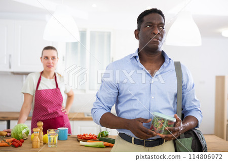 Man holds a jar of vegetables and salad prepared by his caring wife Man holds a jar of vegetables and salad prepared by his caring wife 114806972