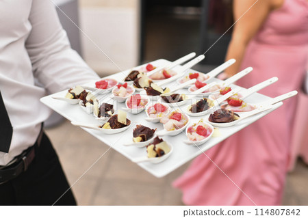 A waiter serving small appetizers at a wedding A waiter serving small appetizers at a wedding 114807842