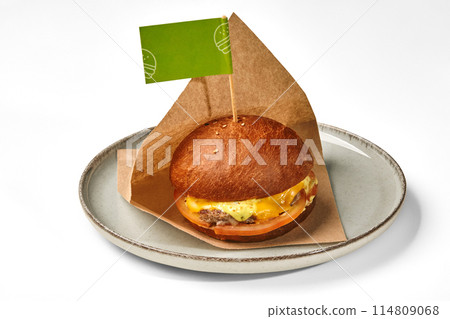 Hamburger with beef patty in paper wrap on plate 114809068