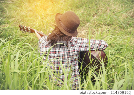 Young women playing acoustic guitar outdoor in green park. Woman person playing acoustic guitar music instrument at home, young Asian musician girl lifestyle in beautiful nature. Happy guitarist 114809193