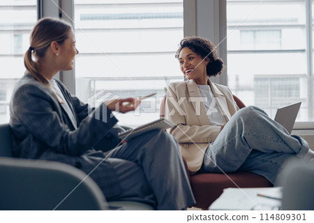 Smiling woman office worker discussing new project with colleague during working day in coworking Smiling woman office worker discussing new project with colleague during working day in coworking 114809301