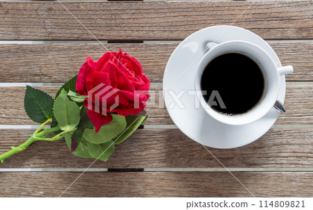 Tabletop black coffee cup red rose on wood table background with empty copy space. Espresso shot caffeine hot coffee cup in cafe. Top view Black caffeine dark beverage in cafeteria with copy space Tabletop black coffee cup red rose on wood table background with empty copy space. Espresso shot caffeine hot coffee cup in cafe. Top view Black caffeine dark beverage in cafeteria with copy space 114809821