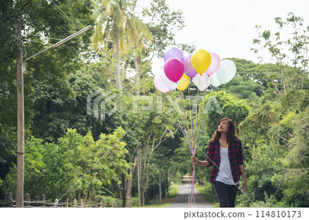 Cheerful cute girl holding balloons running on green meadow white cloud and blue sky with happiness. Hands holding vibrant air balloons play on birthday party happy times summer on sunlight outdoor Cheerful cute girl holding balloons running on green meadow white cloud and blue sky with happiness. Hands holding vibrant air balloons play on birthday party happy times summer on sunlight outdoor 114810173