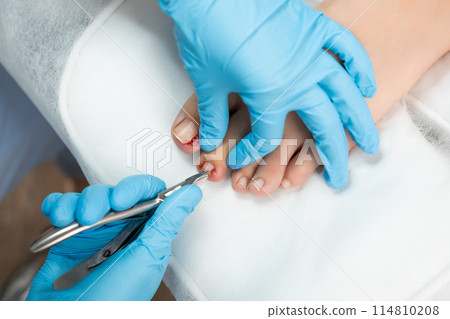 Professional medical pedicure using special nail instruments in the clinic. Professional medical pedicure using special nail instruments in the clinic. 114810208