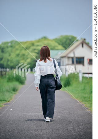 Back view of a young woman walking along the river Back view of a young woman walking along the river 114810360