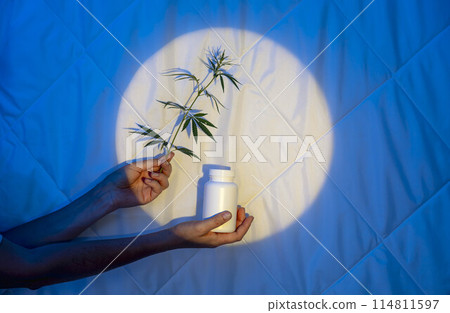 hand delicately holds herb stem next to medicine bottle, reflecting the serene and balanced approach of herbal healing, blue background hand delicately holds herb stem next to medicine bottle, reflecting the serene and balanced approach of herbal healing, blue background 114811597