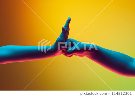 Child gesturing with hands against gradient green yellow background in neon light. Fist to palm Child gesturing with hands against gradient green yellow background in neon light. Fist to palm 114812301