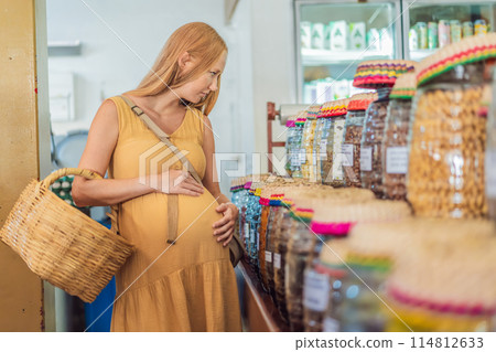 A pregnant woman is at a fruit stand in a grocery store Pregnant woman buying organic vegetables and fruits at Mexican style farmers market A pregnant woman is at a fruit stand in a grocery store Pregnant woman buying organic vegetables and fruits at Mexican style farmers market 114812633