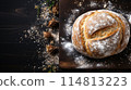 Artisanal Sourdough Bread Freshly Baked on a Rustic Wooden Board Amidst Flour Dust 114813223