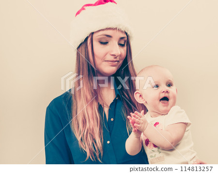 Mother wearing santa hat holding baby 114813257