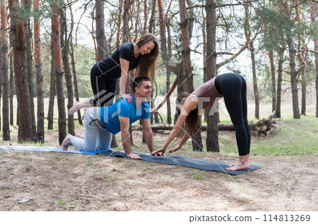 Three people standing in an elaborate acro yoga pose. 114813269