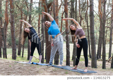 A group of three people doing exercises in the forest. A group of three people doing exercises in the forest. 114813275