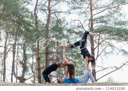 Three people standing in an elaborate acro yoga pose. 114813280