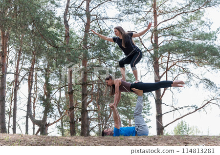 Three people standing in an elaborate acro yoga pose. Three people standing in an elaborate acro yoga pose. 114813281