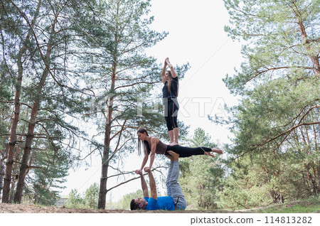 Three people standing in an elaborate acro yoga pose. Three people standing in an elaborate acro yoga pose. 114813282
