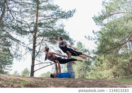 Three people standing in an elaborate acro yoga pose. Three people standing in an elaborate acro yoga pose. 114813283