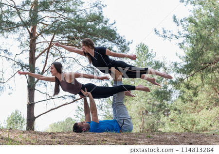 Three people standing in an elaborate acro yoga pose. Three people standing in an elaborate acro yoga pose. 114813284