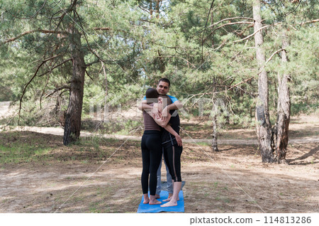 A man and two girls in sportswear hug after doing exercises in the forest. A man and two girls in sportswear hug after doing exercises in the forest. 114813286