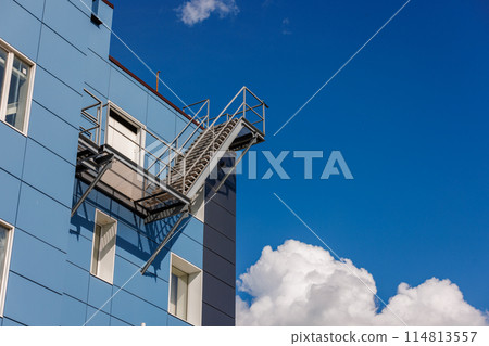 Azure building with a side fire escape, under a sky with fluffy clouds Azure building with a side fire escape, under a sky with fluffy clouds 114813557