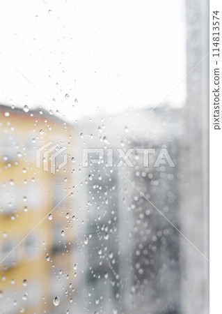 Raindrops on the window glass from the side of the apartment during the day 114813574