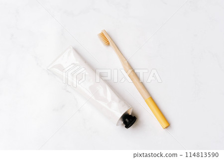 Top view of white metal tube without label and toothbrush on white background Top view of white metal tube without label and toothbrush on white background 114813590